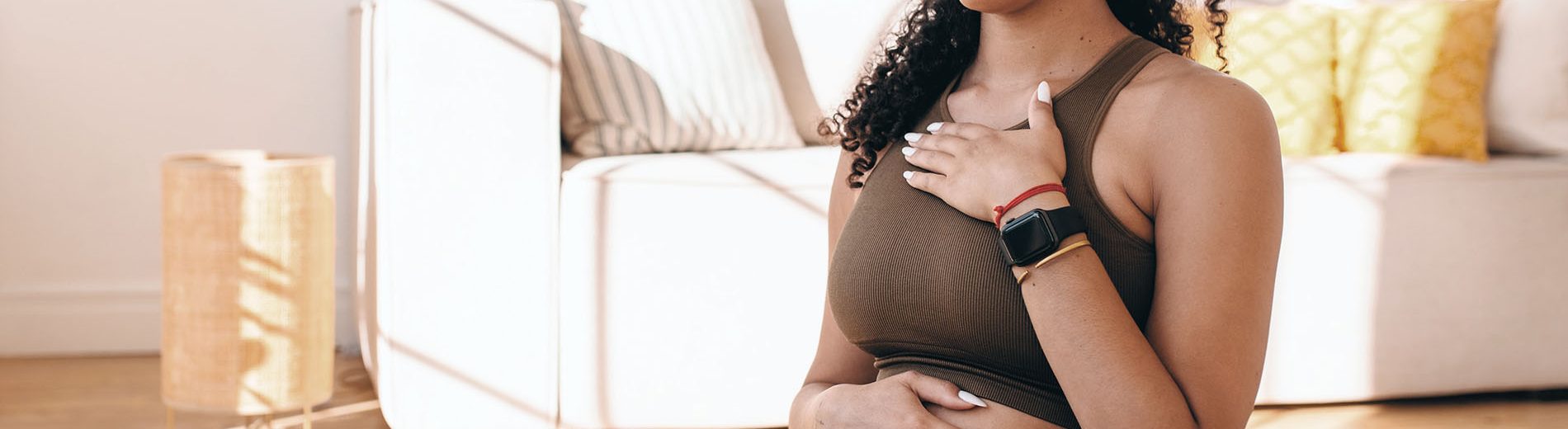 Imagem de uma gestante sentada no chão, com os olhos fechados, uma mão sobre a barriga e outra no peito. Ela está com as pernas cruzadas e controlando a respiração, uma das técnicas utilizadas para aliviar a dor do parto.