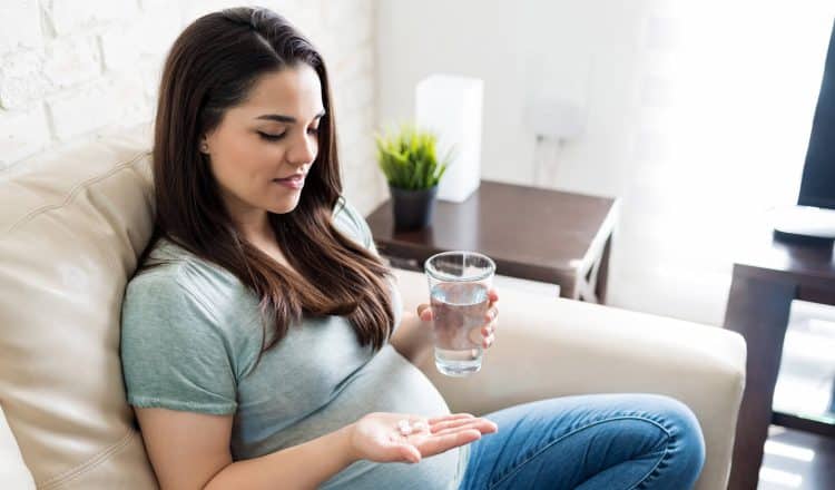Mulher tomando suplemento de ácido fólico na gravidez