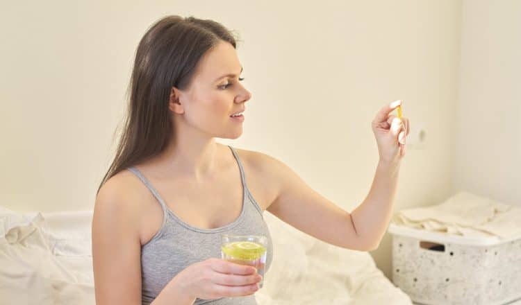 Mulher grávida tomando seu suplemento de ômega 3.