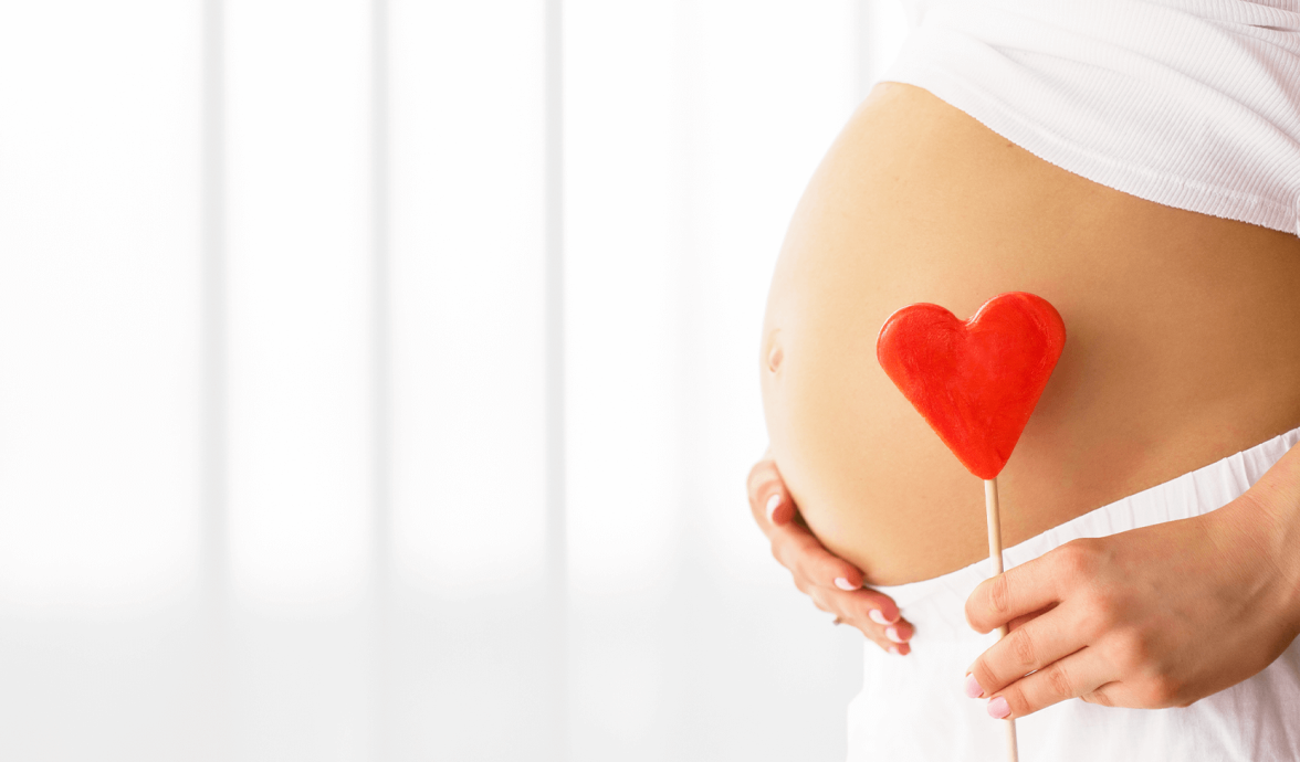 barriga de gestante segurando um enfeite de coração para representar a importância da suplementação na gravidez