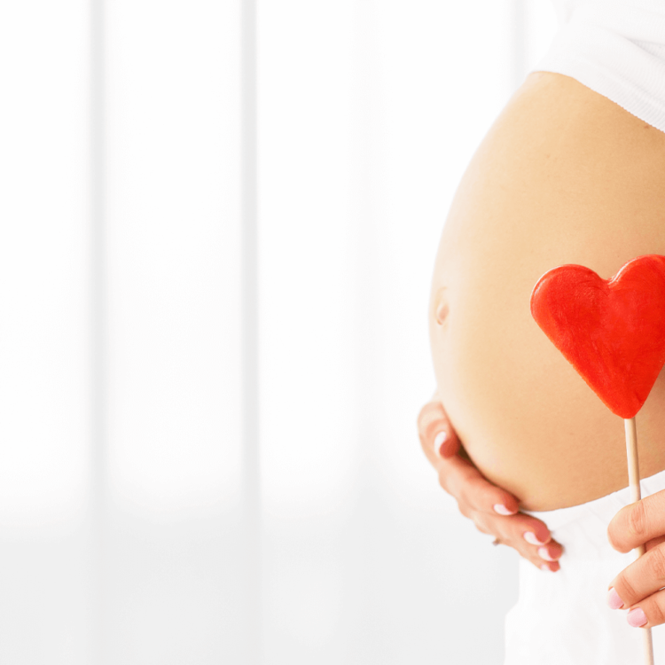 barriga de gestante segurando um enfeite de coração para representar a importância da suplementação na gravidez
