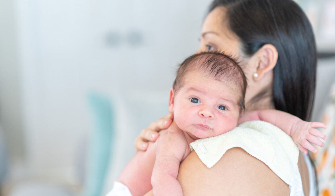 Mãe segurando filho no colo como forma de evitar refluxo em bebês