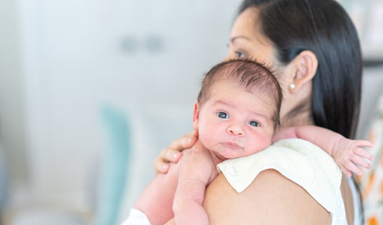 Mãe segurando filho no colo como forma de evitar refluxo em bebês