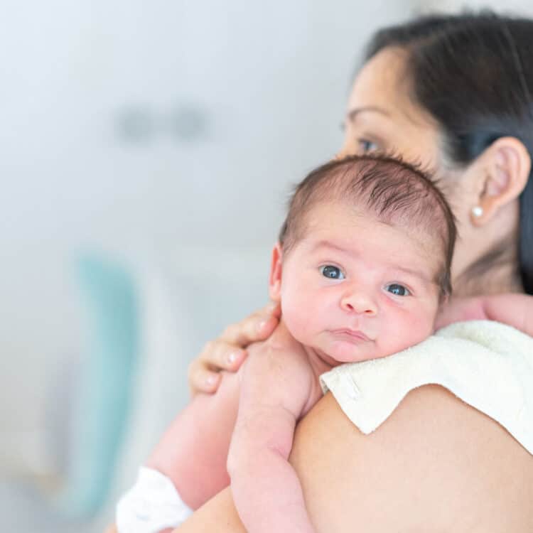 Mãe segurando filho no colo como forma de evitar refluxo em bebês