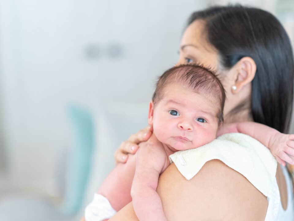 Mãe segurando filho no colo como forma de evitar refluxo em bebês