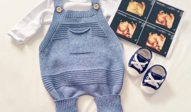 Imagem com uma roupinha de bebê azul, sapatinhos em azul e branco e uma imagem de ultrassom. Os elementos estão espalhados em cima de um fundo branco.