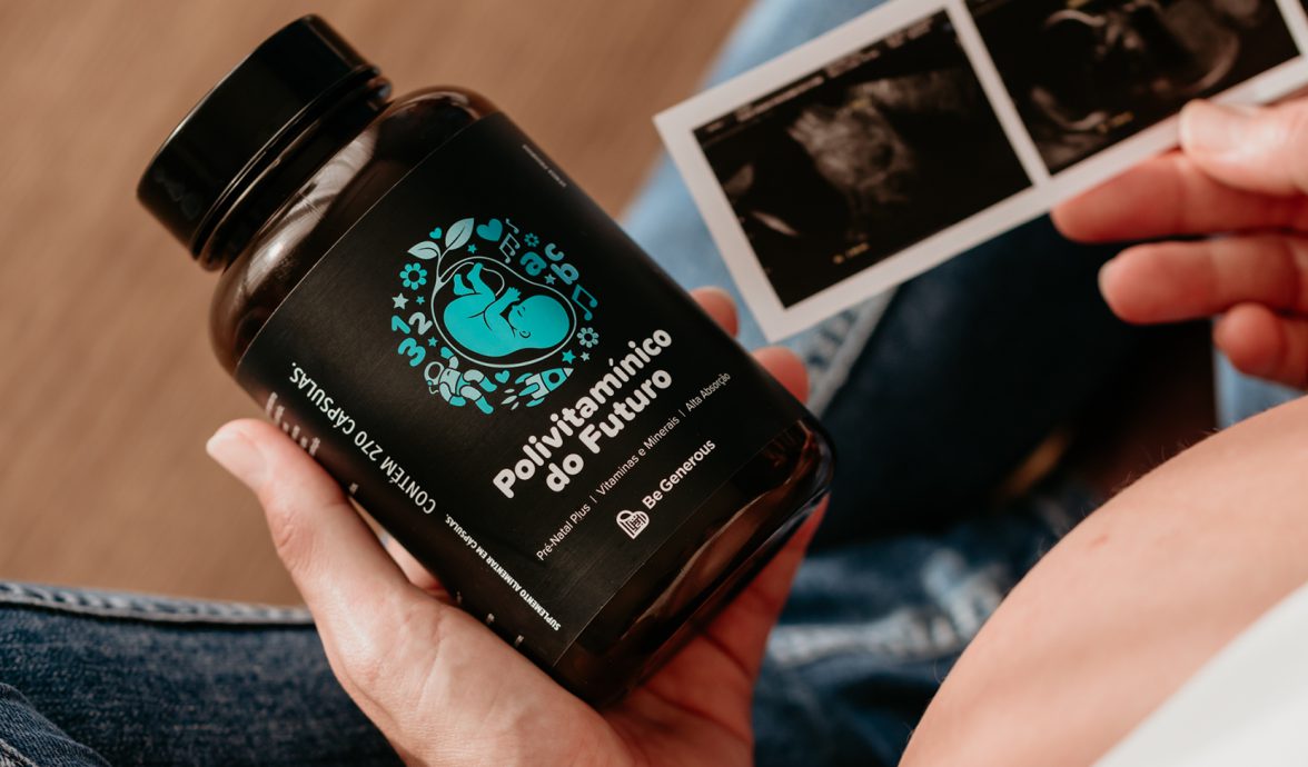 Imagem fechada do Polivitamínico do Futuro, um dos suplementos do projeto Be Generous enviado para Uruguaiana. Ele está na mão esquerda de uma gestante. A imagem está fechada na mão para mostrar o suplemento. É possível ver uma pequena parte da barriga da gestante que,na outra mão, segura uma imagem de ultrassom.